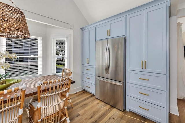 kitchen with stainless steel fridge, light wood-type flooring, and lofted ceiling