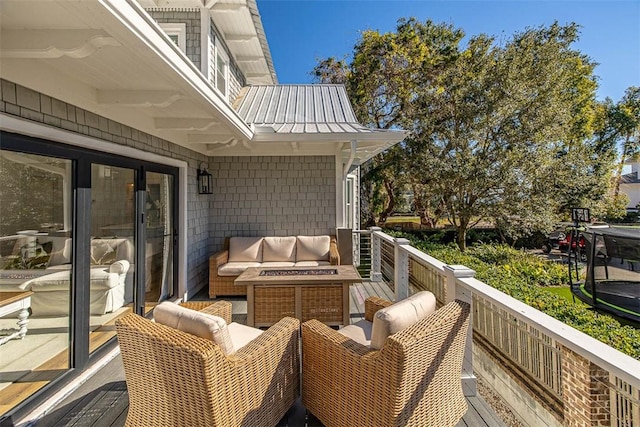 wooden balcony with a deck and an outdoor living space with a fire pit