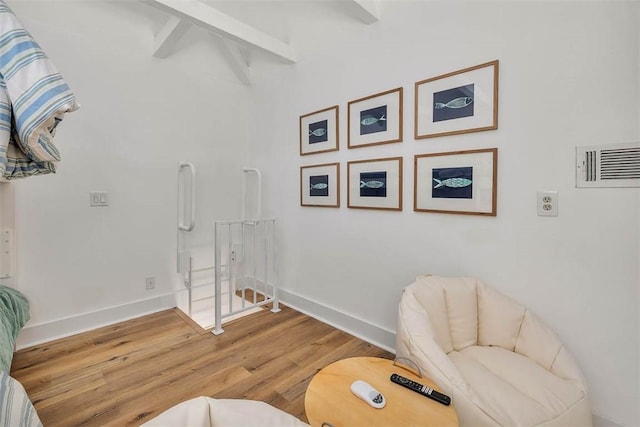 sitting room with beamed ceiling and wood-type flooring