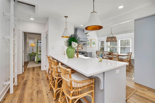 kitchen featuring pendant lighting, light hardwood / wood-style floors, a kitchen bar, and kitchen peninsula