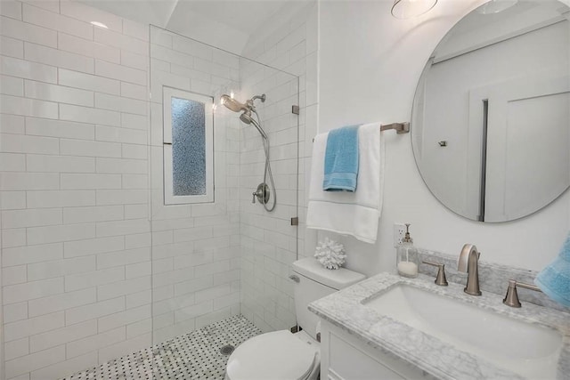 bathroom featuring a tile shower, vanity, and toilet