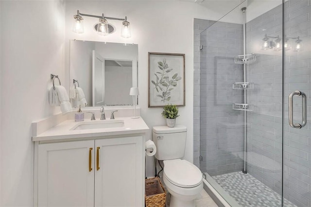 bathroom featuring vanity, a shower with shower door, and toilet