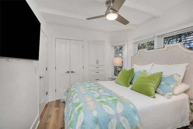 bedroom with beam ceiling, ceiling fan, a closet, and light hardwood / wood-style floors