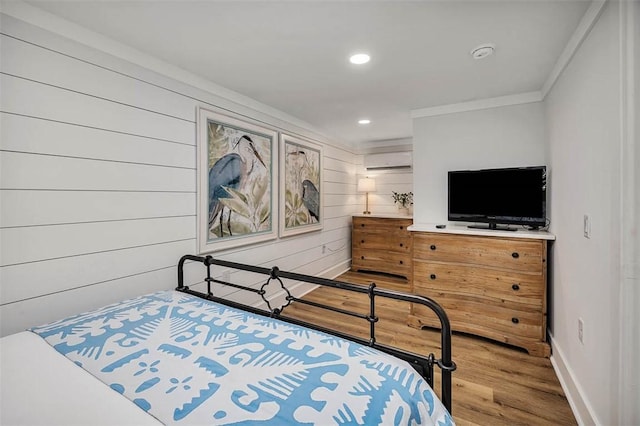 bedroom with an AC wall unit, wooden walls, hardwood / wood-style floors, and ornamental molding