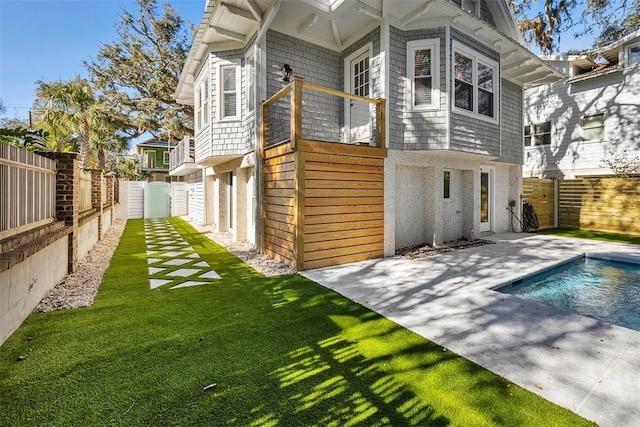 back of property featuring a patio and a fenced in pool