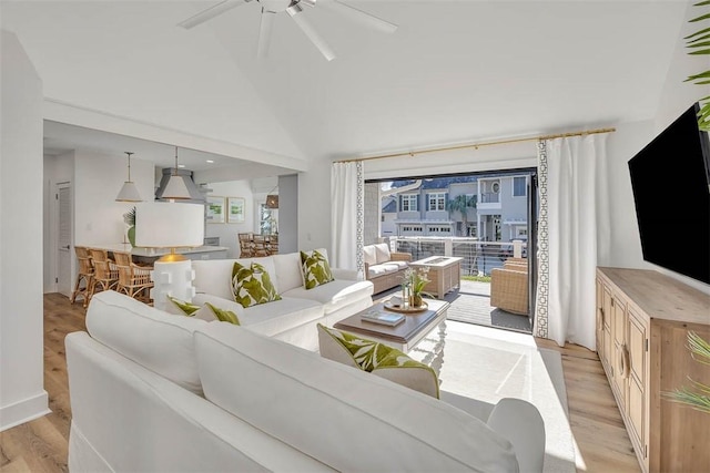 living room featuring ceiling fan, light hardwood / wood-style floors, and a high ceiling