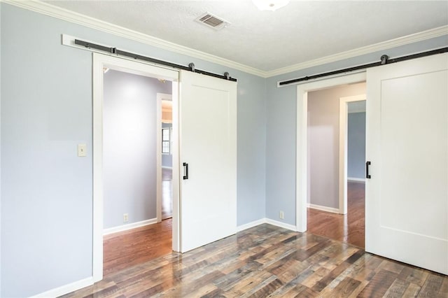 1878 Blalock Ave, Waycross, GA 31503 - unfurnished bedroom featuring a barn door, wood finished floors, crown molding, and baseboards