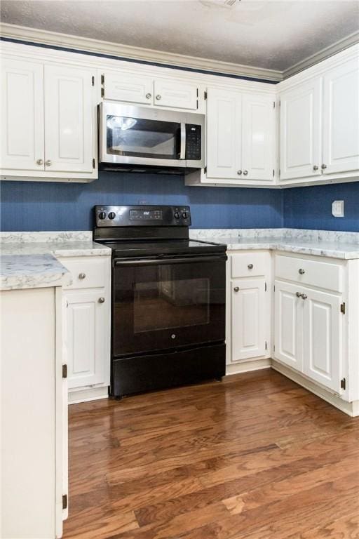 1878 Blalock Ave, Waycross, GA 31503 - kitchen featuring black range with electric cooktop, stainless steel microwave, white cabinetry, and wood finished floors