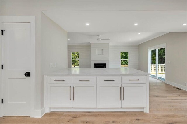 134 Newfield St, Saint Simons Island, GA 31522 - kitchen featuring light stone countertops, white cabinets, a peninsula, light wood finished floors, and open floor plan