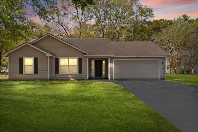 ranch-style house featuring a garage, aphalt driveway, and a lawn