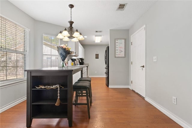 dining room with an inviting chandelier, visible vents, baseboards, and wood finished floors