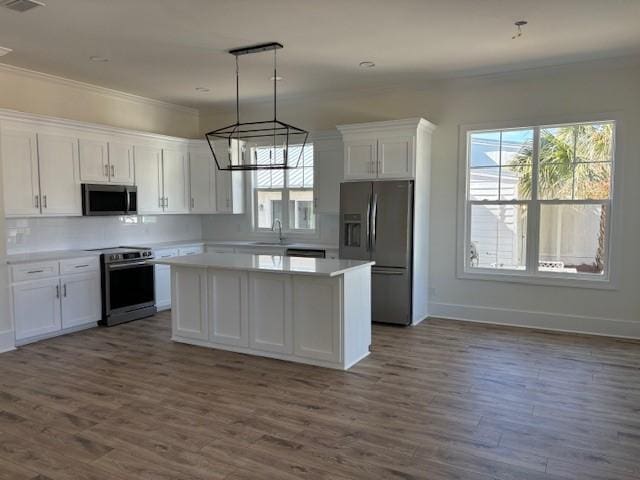 kitchen featuring sink, a center island, hanging light fixtures, stainless steel appliances, and white cabinets