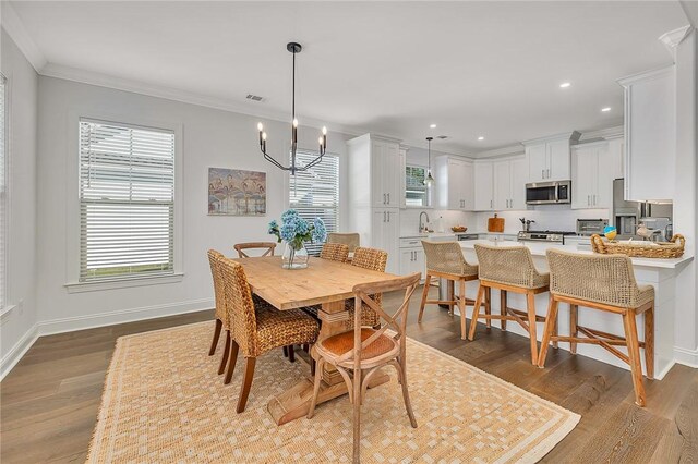 506 Conservation Dr, Saint Simons Island, GA 31522 - dining space featuring wood finished floors, ornamental molding, recessed lighting, baseboards, and a chandelier