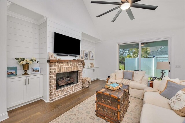 506 Conservation Dr, Saint Simons Island, GA 31522 - living area with dark wood finished floors, a ceiling fan, lofted ceiling, and a brick fireplace