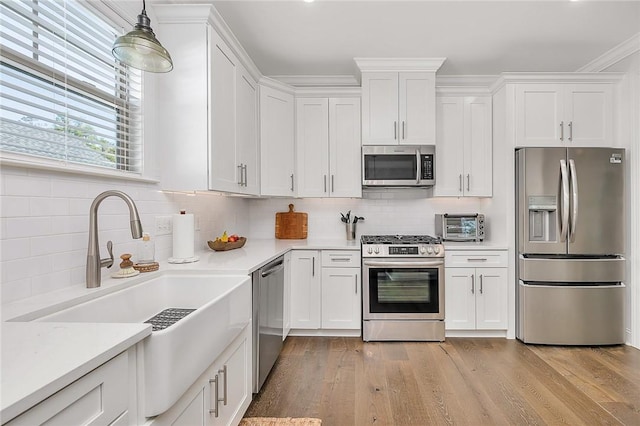 506 Conservation Dr, Saint Simons Island, GA 31522 - kitchen with appliances with stainless steel finishes, white cabinets, light countertops, tasteful backsplash, and light wood-style flooring