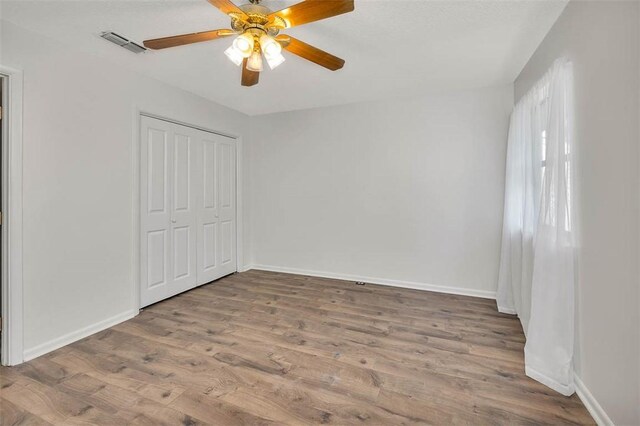 unfurnished bedroom with a closet, hardwood / wood-style flooring, and ceiling fan