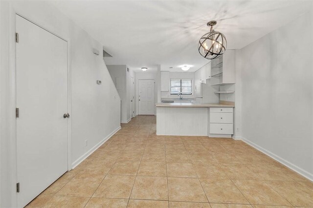 kitchen featuring a notable chandelier, decorative light fixtures, white cabinets, and light tile patterned floors