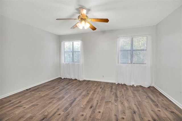 unfurnished room with dark hardwood / wood-style floors, a healthy amount of sunlight, and ceiling fan