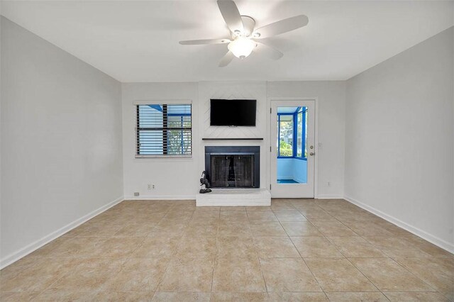 unfurnished living room featuring light tile patterned flooring, a brick fireplace, plenty of natural light, and ceiling fan