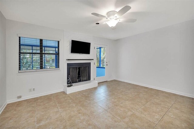 unfurnished living room featuring a fireplace, ceiling fan, and light tile patterned flooring