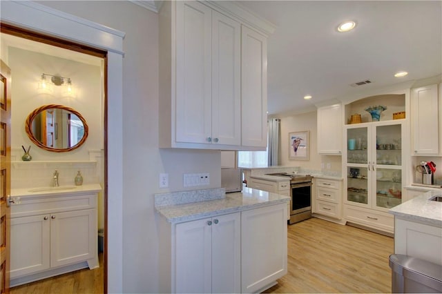 kitchen featuring white cabinetry, sink, and stainless steel range with electric stovetop