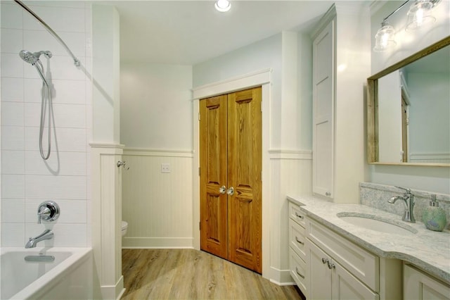 full bathroom with hardwood / wood-style floors, vanity,  shower combination, and toilet