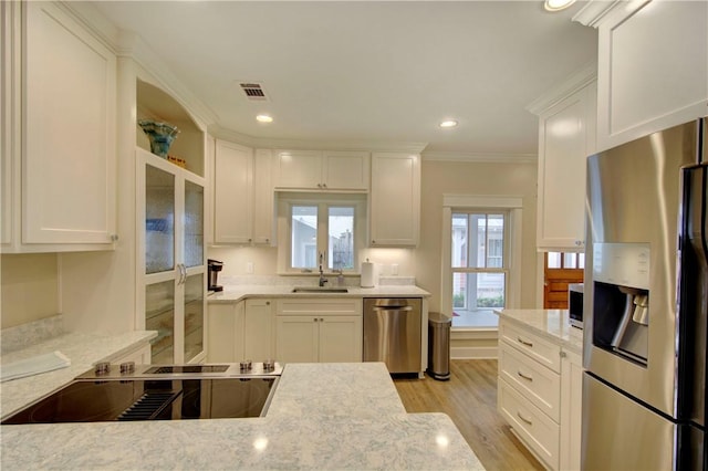 kitchen featuring white cabinets, sink, ornamental molding, light stone counters, and stainless steel appliances