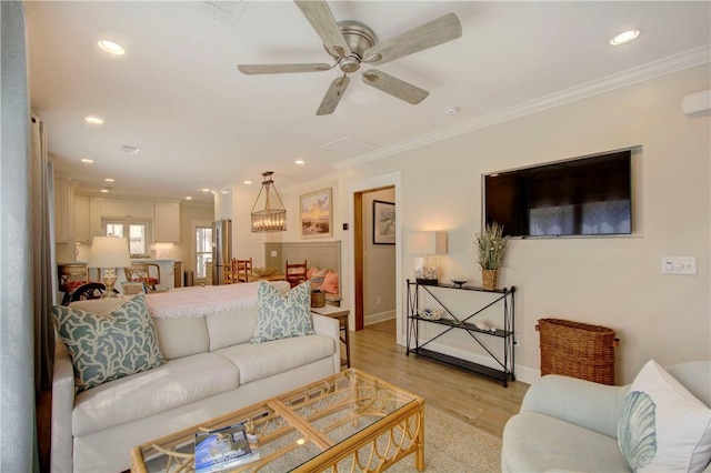 living room featuring ceiling fan with notable chandelier, light hardwood / wood-style floors, and crown molding