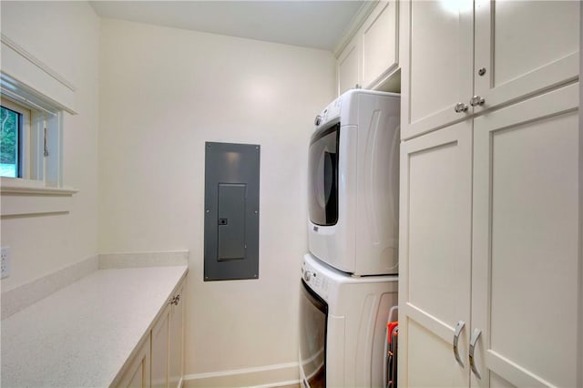 clothes washing area with cabinets, stacked washer and dryer, and electric panel