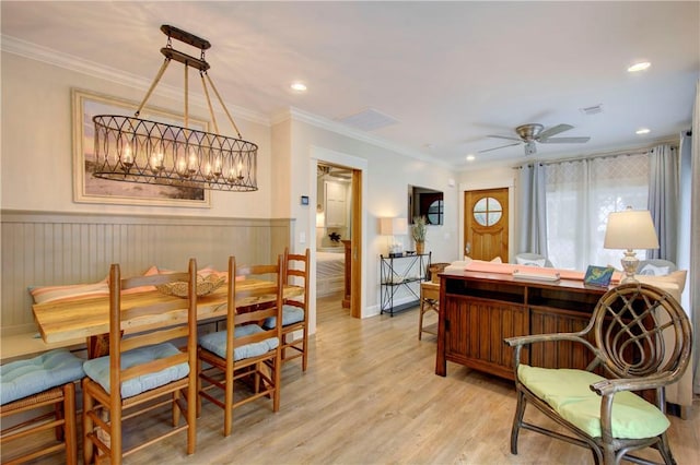 dining area with ornamental molding, ceiling fan with notable chandelier, and light wood-type flooring