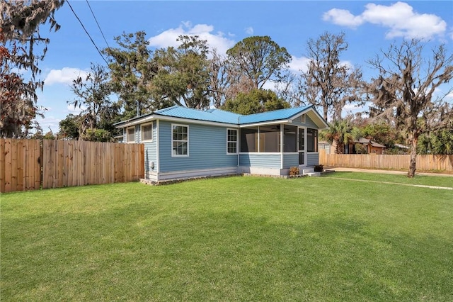 view of front of home with a fenced backyard, a front lawn, and a sunroom