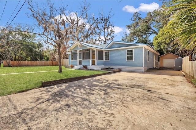 view of front facade featuring a garage, a front lawn, a sunroom, an outdoor structure, and fence