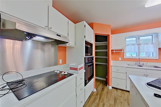 2204 Gibbs St, Waycross, GA 31503 - kitchen featuring black appliances, light wood-style flooring, white cabinetry, light countertops, and under cabinet range hood