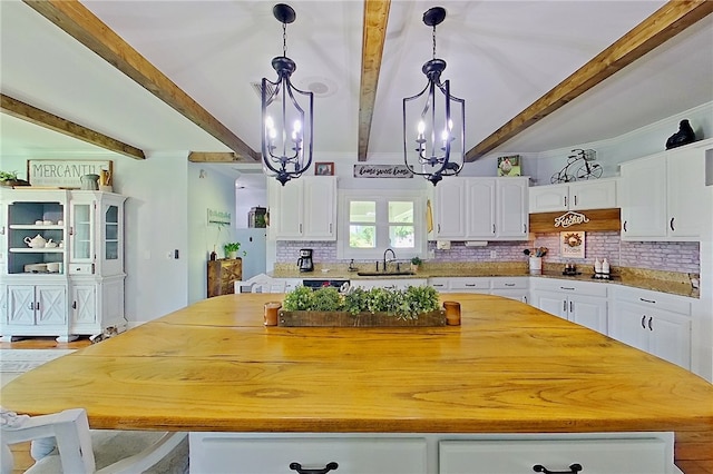 2204 Gibbs St, Waycross, GA 31503 - kitchen featuring a chandelier, a kitchen island, beamed ceiling, white cabinetry, and light countertops