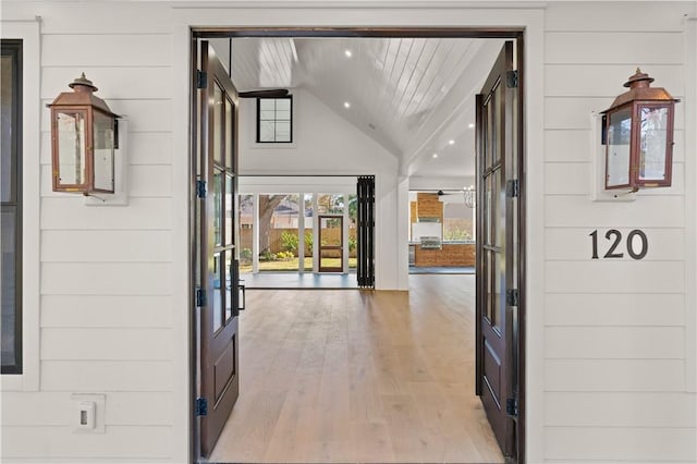 foyer entrance with french doors, light hardwood / wood-style flooring, vaulted ceiling, wooden walls, and wood ceiling