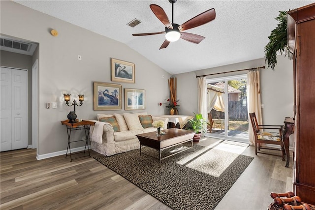 living room with hardwood / wood-style flooring, ceiling fan, lofted ceiling, and a textured ceiling