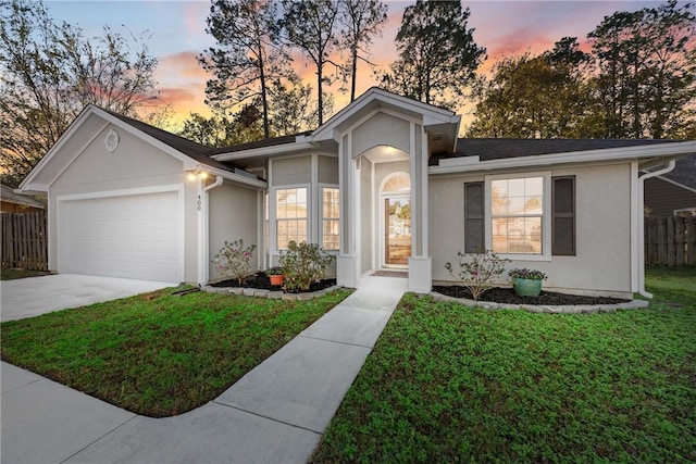 single story home featuring a garage and a lawn