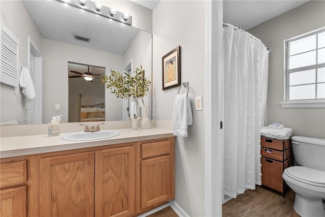 bathroom featuring ceiling fan, toilet, wood-type flooring, and a textured ceiling