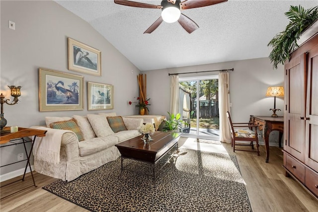 living room featuring a textured ceiling, ceiling fan, light hardwood / wood-style flooring, and lofted ceiling