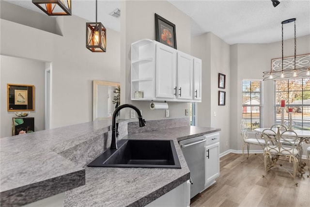 kitchen featuring stainless steel dishwasher, sink, high vaulted ceiling, white cabinetry, and hanging light fixtures