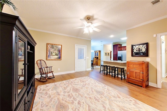 sitting room featuring crown molding, light hardwood / wood-style flooring, ceiling fan, and a textured ceiling