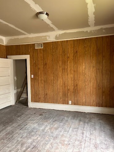 spare room featuring wooden walls and hardwood / wood-style floors