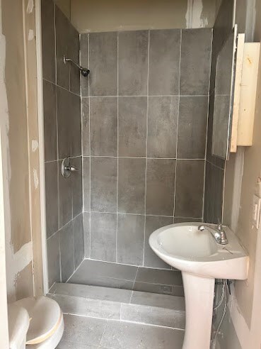 bathroom featuring toilet and tiled shower