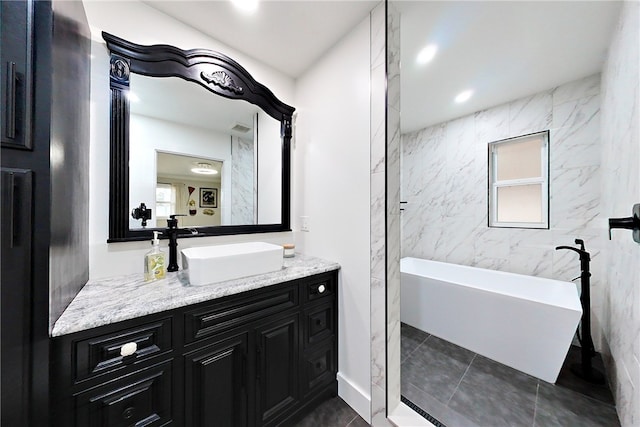 bathroom with a freestanding tub, vanity, recessed lighting, visible vents, and tile walls