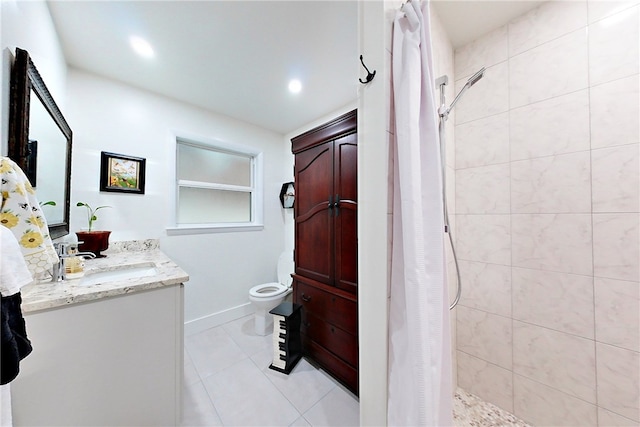 bathroom with vanity, toilet, baseboards, tile patterned floors, and tiled shower