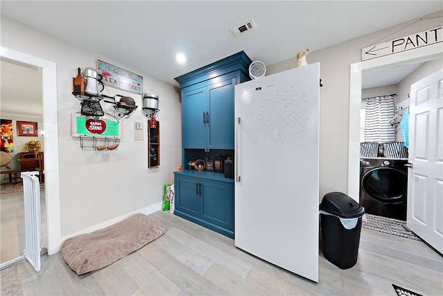 kitchen featuring light wood-style flooring, visible vents, washer / clothes dryer, blue cabinetry, and freestanding refrigerator