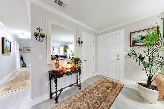 foyer with baseboards, visible vents, and ornamental molding