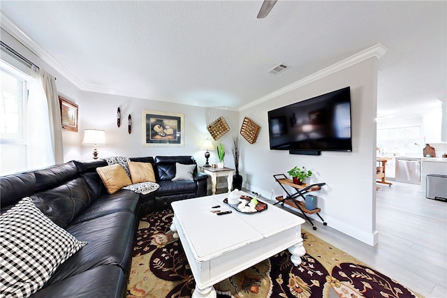living room featuring ornamental molding, baseboards, light wood-style floors, and visible vents