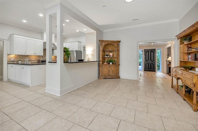 kitchen with decorative backsplash, ornamental molding, white cabinetry, stainless steel refrigerator, and light tile patterned flooring