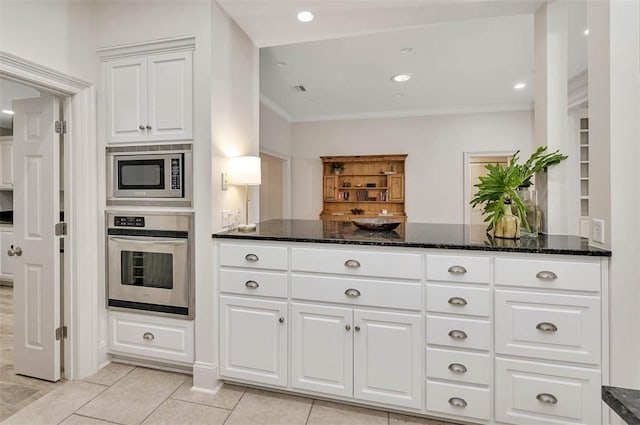 kitchen with kitchen peninsula, ornamental molding, dark stone counters, stainless steel appliances, and white cabinetry